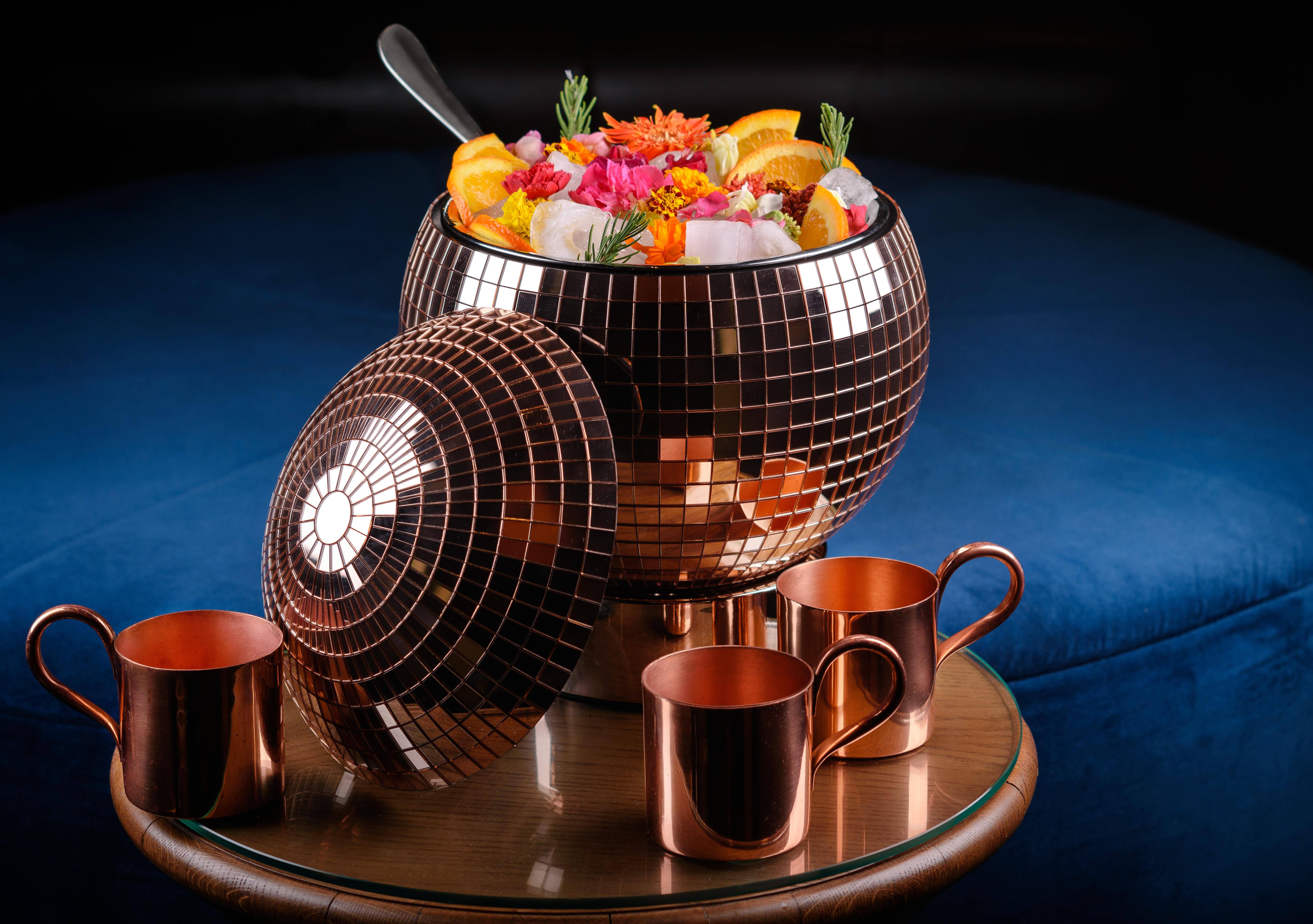Hotel The Palazzo At The Venetian Las Vegas Exterior foto The photo shows a large, brown, disco-ball-shaped bowl filled with colorful fruits, flowers, and ice. The bowl is shiny and reflective, resembling a disco ball. Surrounding the bowl are four copper cups, which are placed on a round wooden table. The 